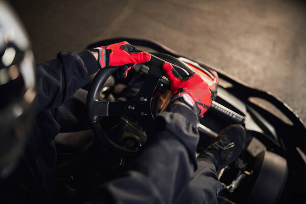 top view of racer in helmet driving go kart car on indoor circuit, motorsport competition concept
