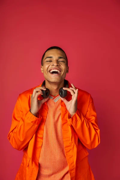 Stijlvolle Afro Amerikaanse Man Oranje Shirt Met Draadloze Koptelefoon Lachen — Stockfoto