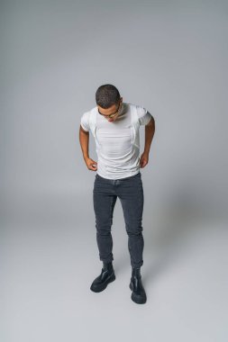 Moda trendi, güneş gözlüklü Afro-Amerikan adam, tişört, elleri gri cepli kot pantolon