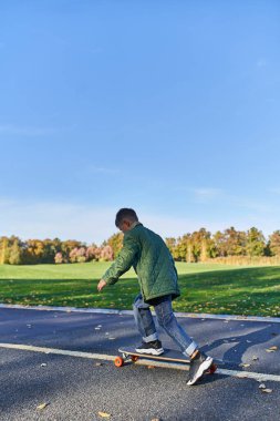 Dış giysili hoş bir çocuk peni panosu, asfalt, park, sonbahar sezonu, sonbahar elbiseli bir çocuk.
