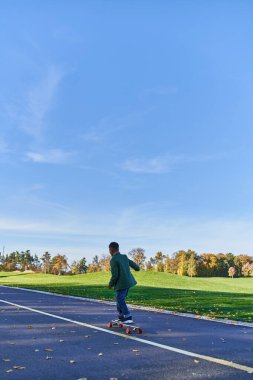 Dış giysili hoş çocuk, peni tahtası, asfalt, park, sonbahar sezonu, sonbahar kıyafetleri içinde çocuk.