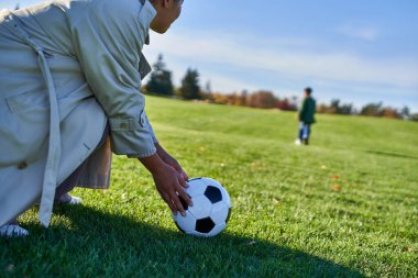 Futbol toplu Afro-Amerikan kadın, oğluna bakan anne, bulanık arka plan, yeşil alan