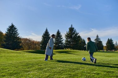 Neşeli Afrikalı Amerikalı çocuk mutlu annesiyle futbol oynuyor yeşil sahada, futbol, sonbahar, koş
