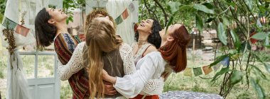 Pozitif çoklu etnik kadınlar şık boho kıyafetleri içinde dışarıda inziva merkezinde sarılıyorlar, afiş.