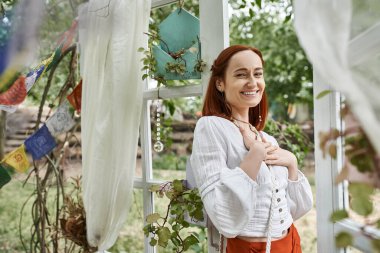 Gülümseyen kadın boho kıyafetli. Avluda kameraya bakıyor. İnziva merkezinde.