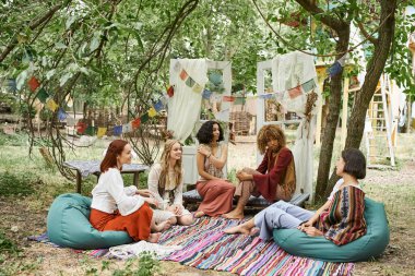 Boho stili çoklu etnik kız arkadaşlar dinlenme merkezinin parkında konuşuyorlar, neşe ve pozitiflik