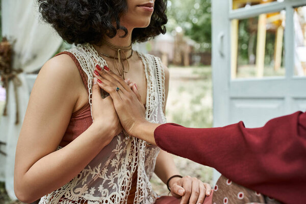 cropped view of multiethnic women practicing meditation outdoors in retreat center