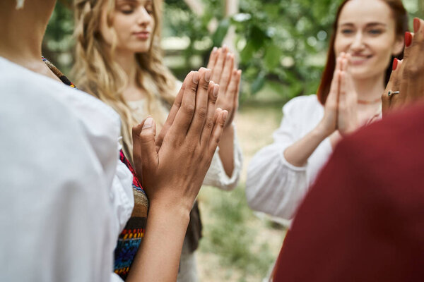 multiethnic women in boho clothes praying and meditating together in retreat center
