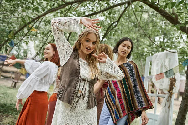 stock image trendy young blonde woman dancing and looking at camera near friends in retreat center
