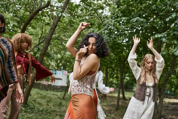 Boho giysileri içinde neşeli, çok kültürlü bir kadın kameraya bakıyor ve inziva merkezinde dans ediyor.
