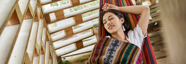 pleased woman in boho style clothes resting in hammock, retreat, harmony, rejuvenation