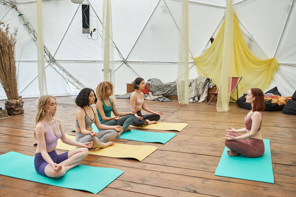 wellness and harmony, multiethnic women meditating in lotus pose in modern retreat center