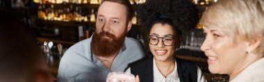 Şaşırmış sakallı adam, neşeli çoklu etnik kadınların yanında iş çıkışı kokteyl barında vakit geçiriyor.
