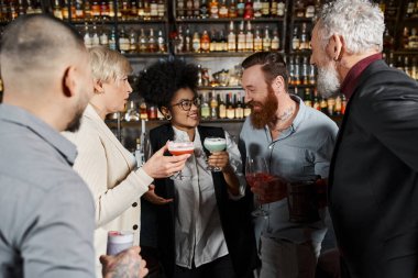 multiethnic colleagues with drinks smiling during conversation in bar, leisure of diverse team clipart