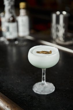 Bar tezgahında kivi dilimli bir bardak lezzetli alkollü süt kokteyli, kokteyl sunumu.