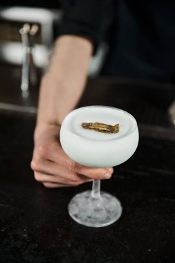 cropped view of bartender presenting glass of milk punch with kiwi slice, cocktail hour in bar clipart