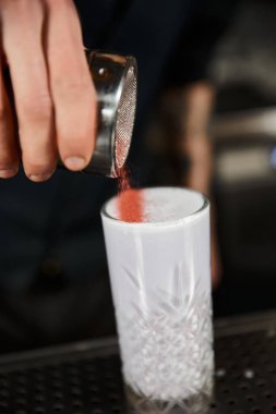 Kırpılmış barmen manzarası bardakta tarçın ve sütlü punç, bar ortamında kokteyl.
