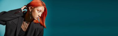 asian woman with red hair and nose piercing posing in oversized blazer on blue backdrop, banner clipart