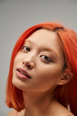 Kızıl saçlı ve yumuşak tenli Asyalı güzel bir kadının kameraya, zarafete baktığı yakın plan.