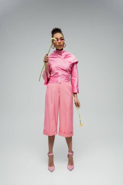 Pembe giysili ve çiçekli güneş gözlüklü Afro-Amerikan kadın.