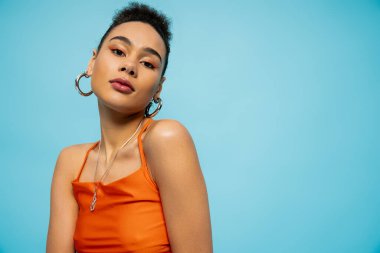 Canlı giysiler içinde genç Afro-Amerikan modelinin portresi ve mavi arka planda parlak makyaj.