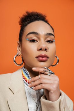 Çekici makyajlı ve kameraya bakan gümüş yüzüklü Afro-Amerikan modelinin portresi.