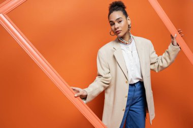 Şık bir moda modeli, şık kıyafetler ve turuncu çerçeveli canlı bir makyaj.