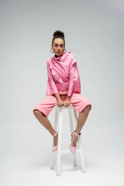 アフリカ系アメリカ人ファッションモデル ピンクの服装とサングラス 椅子に座って灰色にポーズ — ストック写真