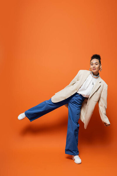 красивая молодая модель в яркой уличной одежде с серьгами на одной ноге