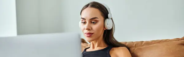 Kablosuz Kulaklıklı Güzel Bir Kadın Dizüstü Bilgisayar Kullanıyor Koltukta Oturuyor — Stok fotoğraf