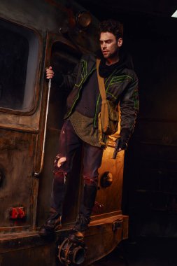man in worn outfit standing with gun on rusty subway carriage, post-apocalyptic life, full length clipart