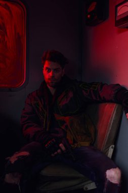 Silahlı bunalımlı adam terk edilmiş metro vagonunda kırmızı ışıkta, kıyamet sonrası konseptinde oturuyor.