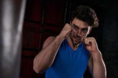 athletic and unshaven man working out with punching bag in dark city, street athlete clipart