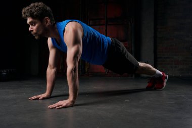 Gece sokağının karanlığında tahta pozisyonunda spor giysileri eğitimi alan güçlü bir adam.