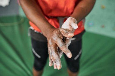 Kaya duvarına tırmanmadan önce spor tebeşiri kullanan turuncu tişörtlü Afro-Amerikan bir adam gördüm.