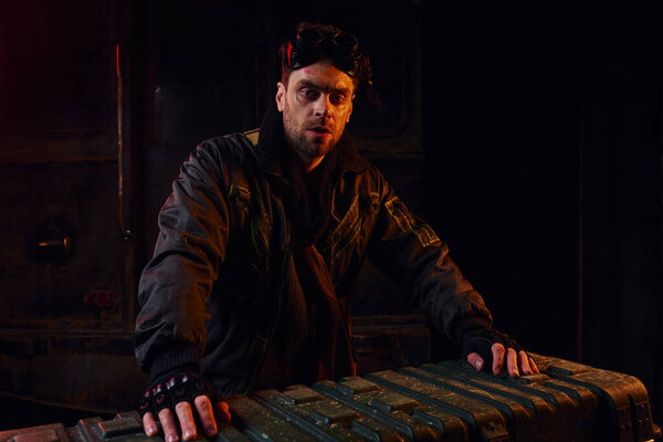 человек в очках и поцарапанное лицо возле оружейной коробки в заброшенном метро, постапокалиптическая концепция