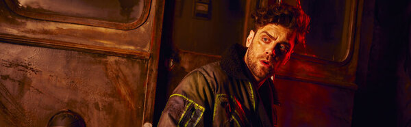 испуганный человек смотрит в сторону ржавой кареты в темном подземном туннеле с красным светом, знамя