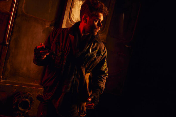 Человек держит запасную часть вагона метро, глядя в красном свете после катастрофы под землёй