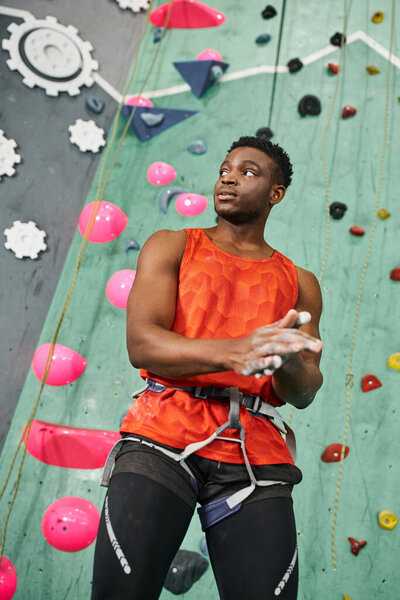 vertical shot of handsome african american man using talc powder with rock wall on backdrop