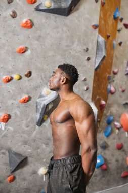 Duvara tırmanan yakışıklı Afro-Amerikalı adamın dikey görüntüsü.