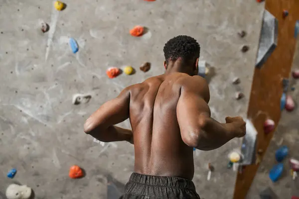 stock image sporty young african american man with his shirt off flexing his muscles near bouldering wall