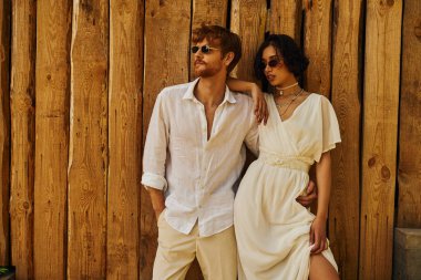 Boho tarzında kırsal bir düğün, gelinlik giymiş Asyalı gelin damat ve güneş gözlüğü takıyor.