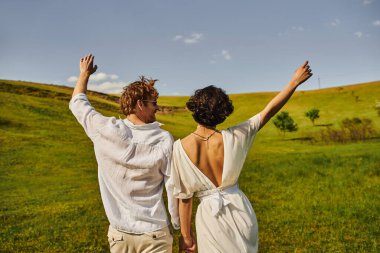 rural wedding, bride in wedding dress holding hands with happy groom in field, just married couple clipart