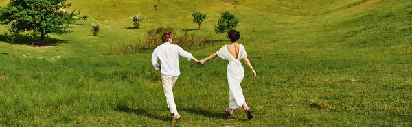 newlyweds holding hands and running in green field, bride and groom in wedding gown, banner
