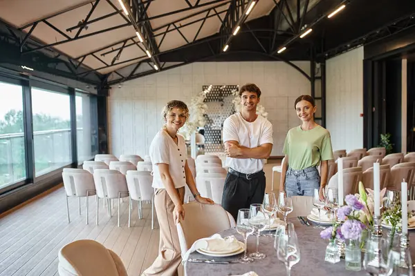 Decoradores Felices Mirando Cámara Cerca Mesa Con Escenario Banquete Sala — Foto de Stock