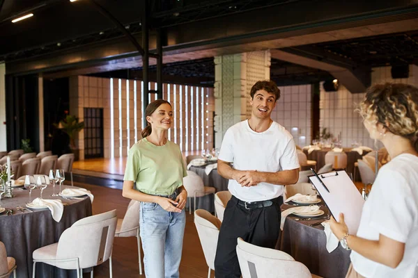 stock image smiling decorators talking to team lead near festive tables in modern decorated banquet hall