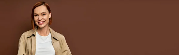 Bej Renkli Trençkotlu Mutlu Kızıl Kadın Kahverengi Arka Planda Kameraya — Stok fotoğraf