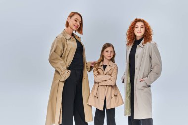 three generation redhead family posing together in autumn coats on grey backdrop, fall fashion clipart