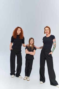 Gri arka planda eşleşen eşleşen elbiseli kızıl saçlı aile, üç kadın jenerasyon.