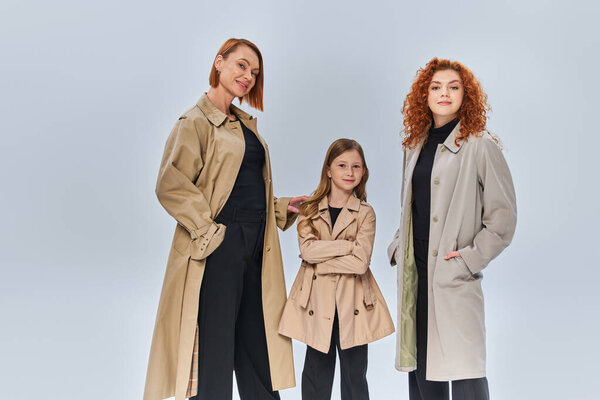 three generation redhead family posing together in autumn coats on grey backdrop, fall fashion